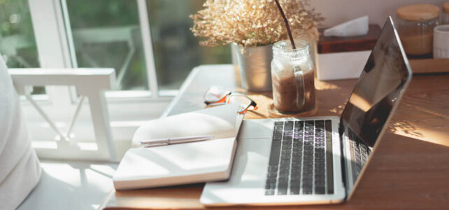 Home office: laptop, book, flowers in sunlight