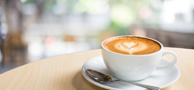 Caffe latte with heart in white cup on table