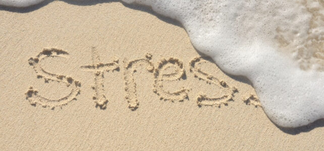 Ocean foam erasing the word Stress in sand